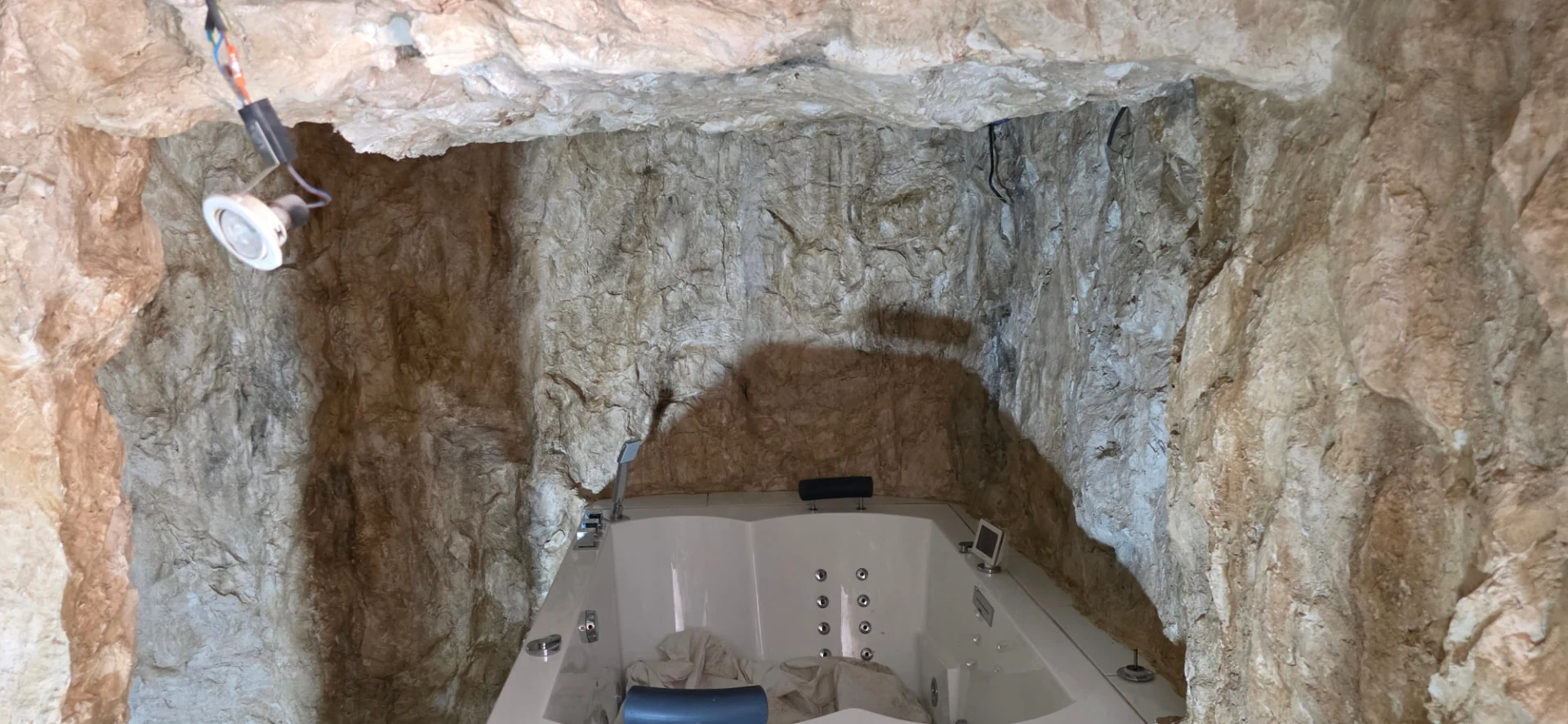 Plafond en faux rochers polyester et éclairage encastré au-dessus de la baignoire balnéo – décoration immersive style grotte naturelle